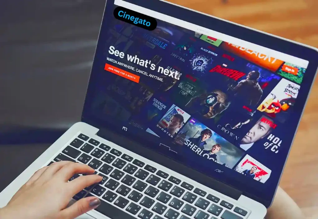 Interface de streaming do Cinegato exibida em um laptop, mostrando filmes e séries disponíveis para assistir no PC.